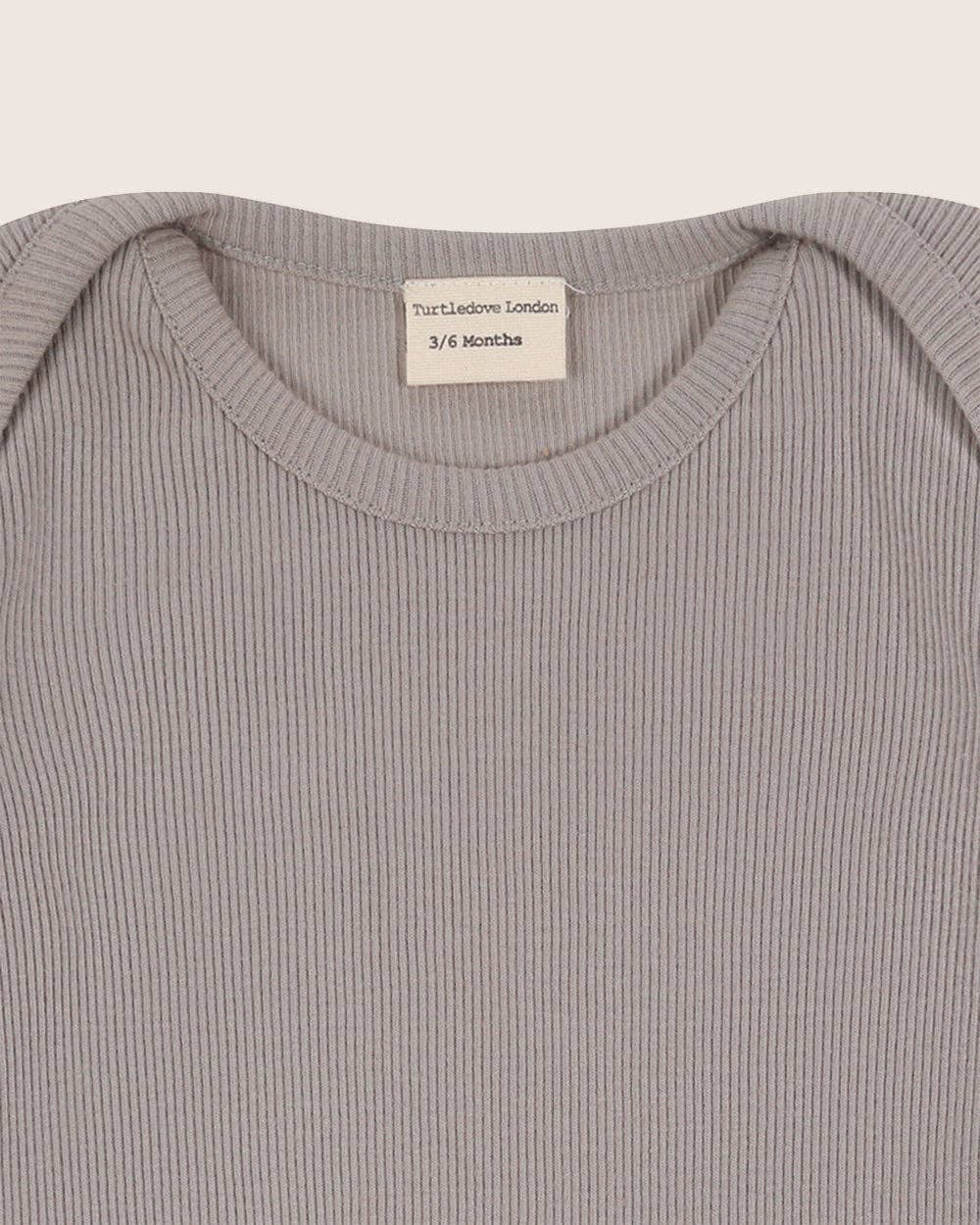 Close-up of a ribbed bodysuit collar with a label on a light gray background