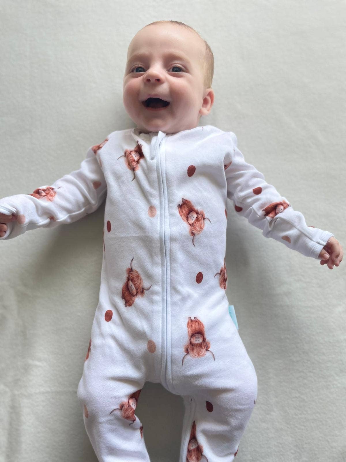 Baby wearing a white sleepsuit with floral patterns on a light background