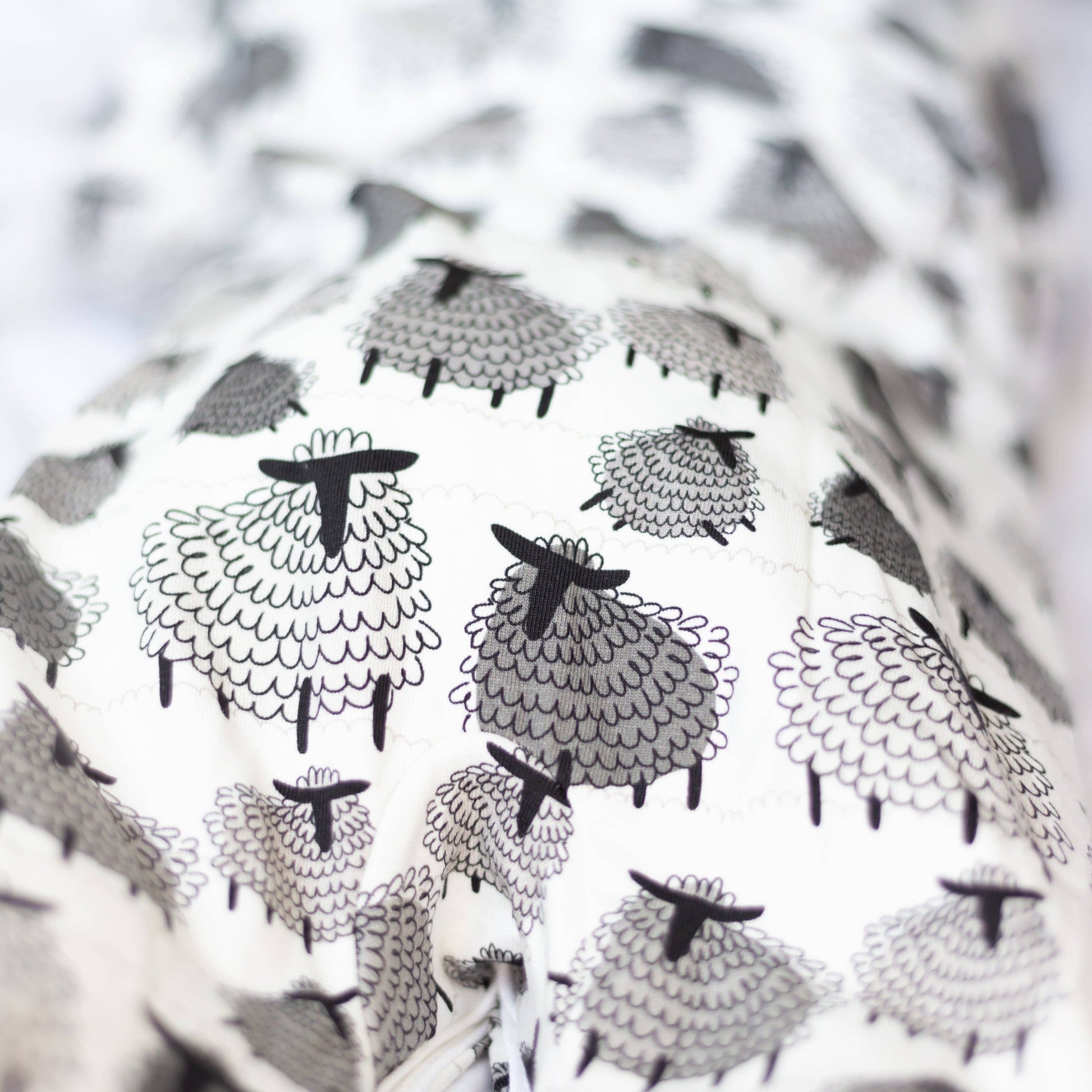 Black and white pattern of sheep on a textured fabric background