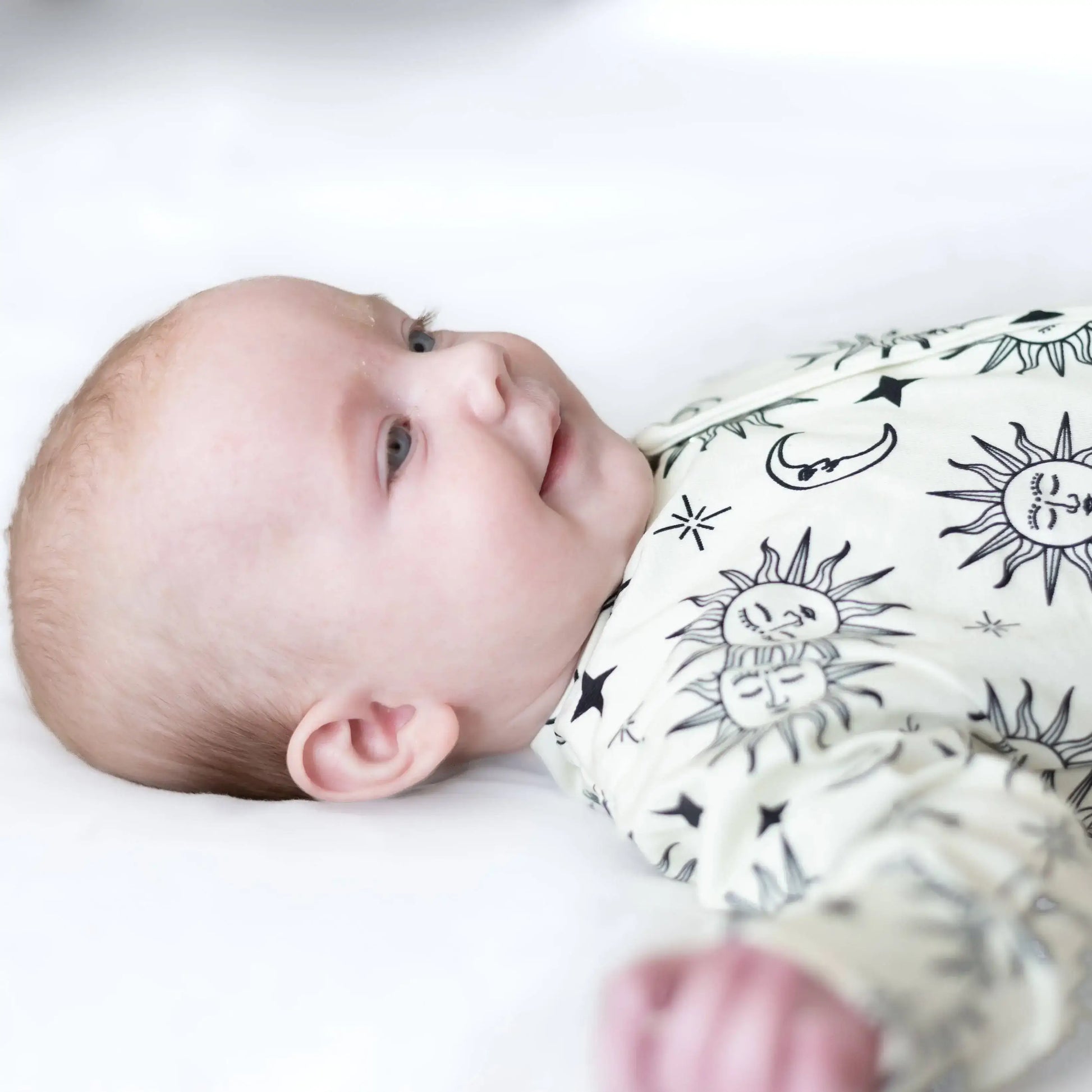 Baby wearing sleepsuit with black and white patterns on a light background