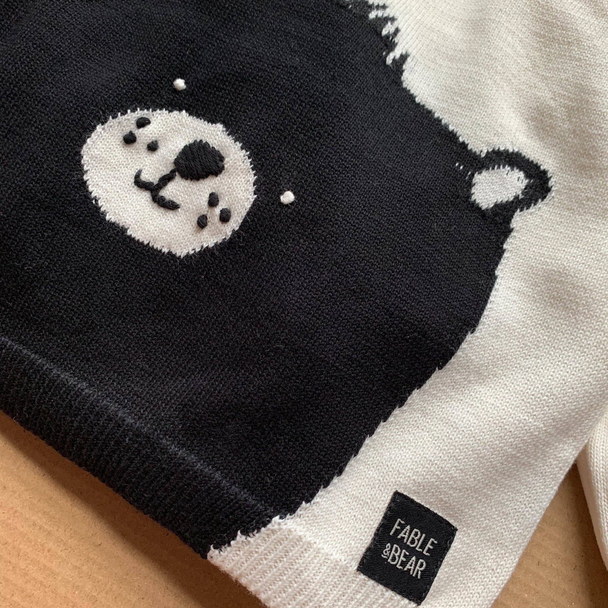 Black and white bear-themed product with 'Fable & Bear' label on a wooden surface