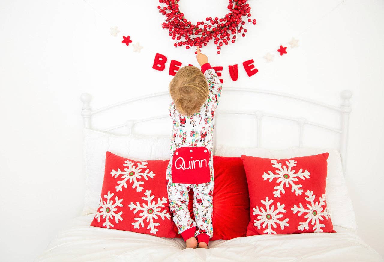 Child in pajamas on a bed with Christmas decorations