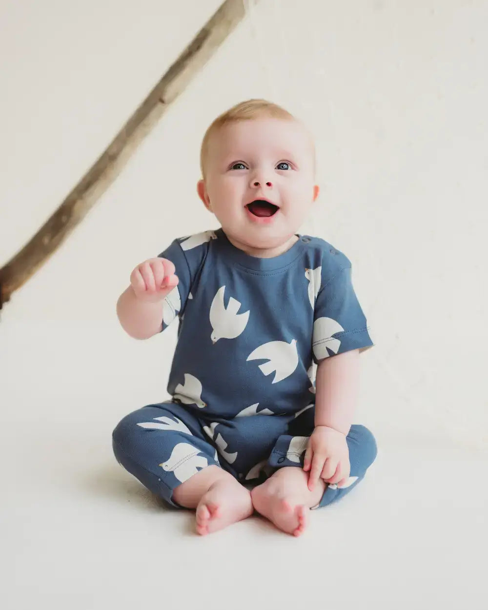 Baby wearing a 100 cotton romper with white patterns on a light background