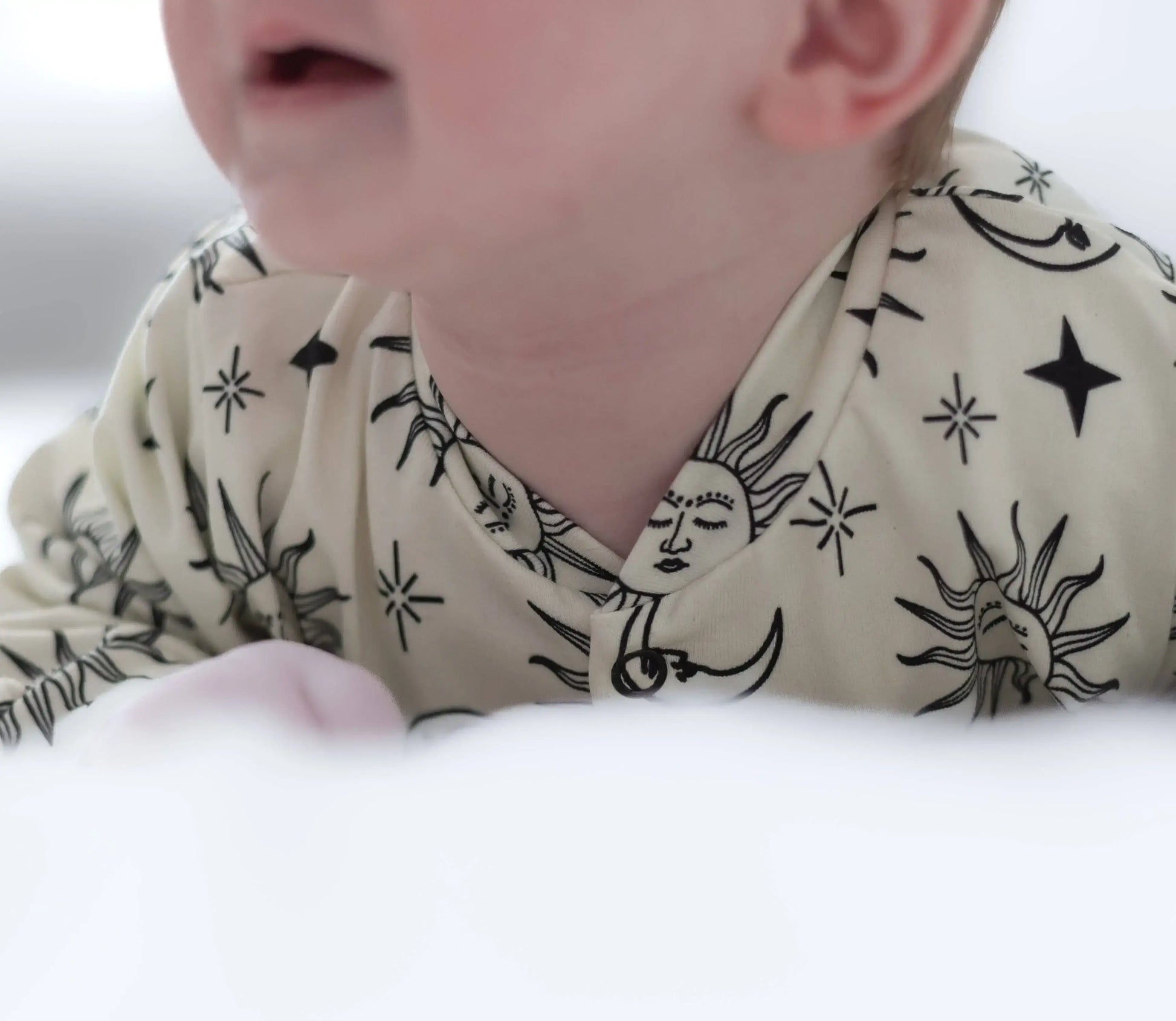 Close-up of a baby wearing a patterned sleepsuit with stars and suns.