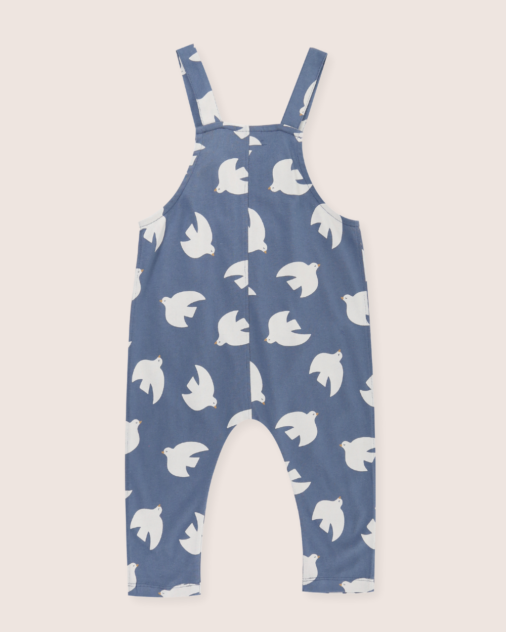 Blue dungaree back with white bird pattern on a beige background