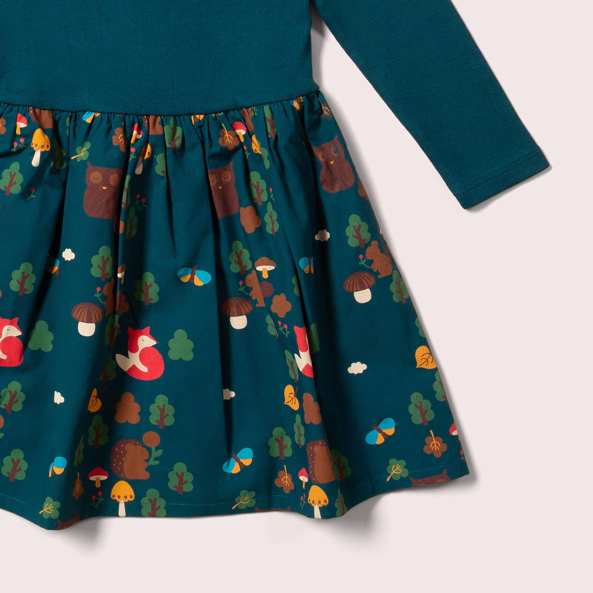 Teal dress with forest-themed pattern on a white background
