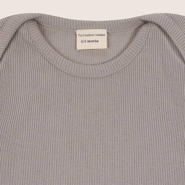 Close-up of a ribbed bodysuit collar with a label on a light gray background