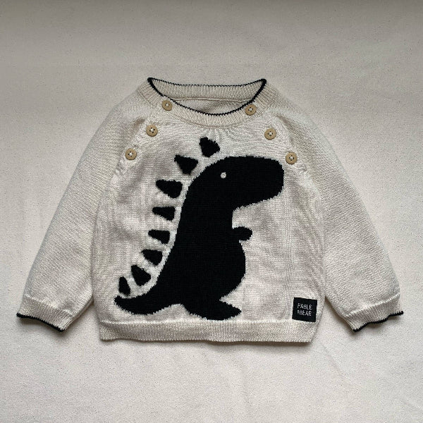 White sweater with black dinosaur design on a light gray background