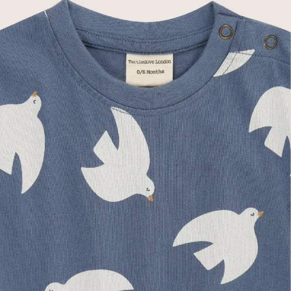 Blue baby shirt with white bird patterns on a light gray background
