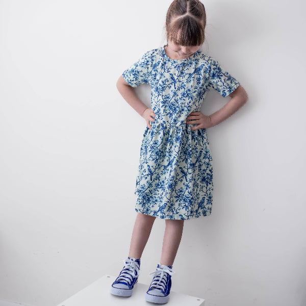 Young girl wearing a blue floral dress against a white background