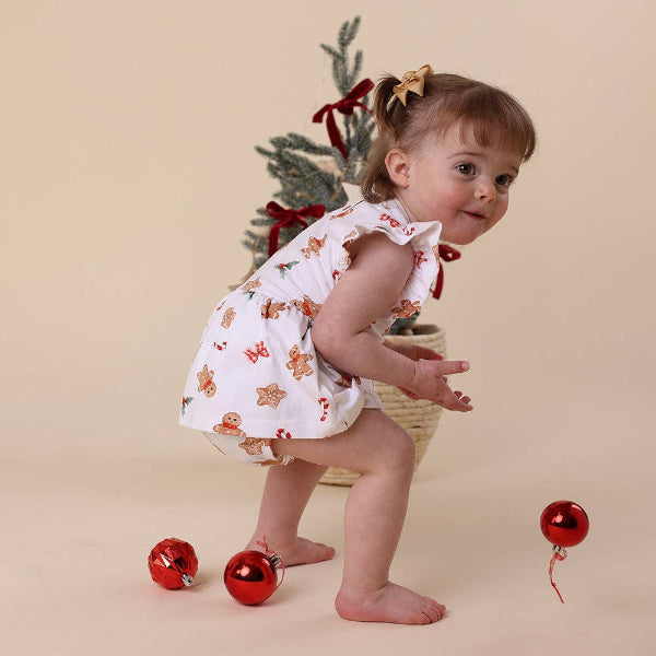 Baby in a festive outfit with Christmas decorations on a beige background