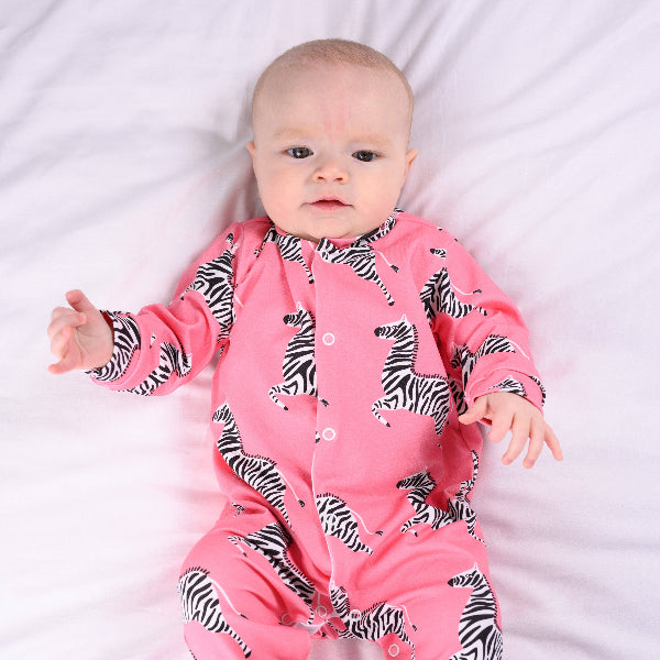 Baby wearing a pink onesie with zebra patterns on a white background