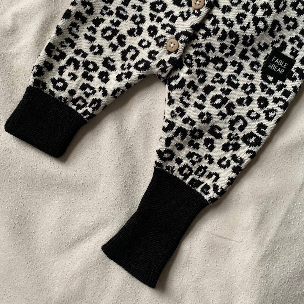 Leopard print baby romper with black cuffs on a light background