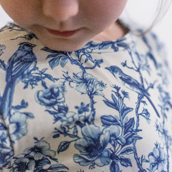 Close-up of a child wearing a blue floral patterned outfit.