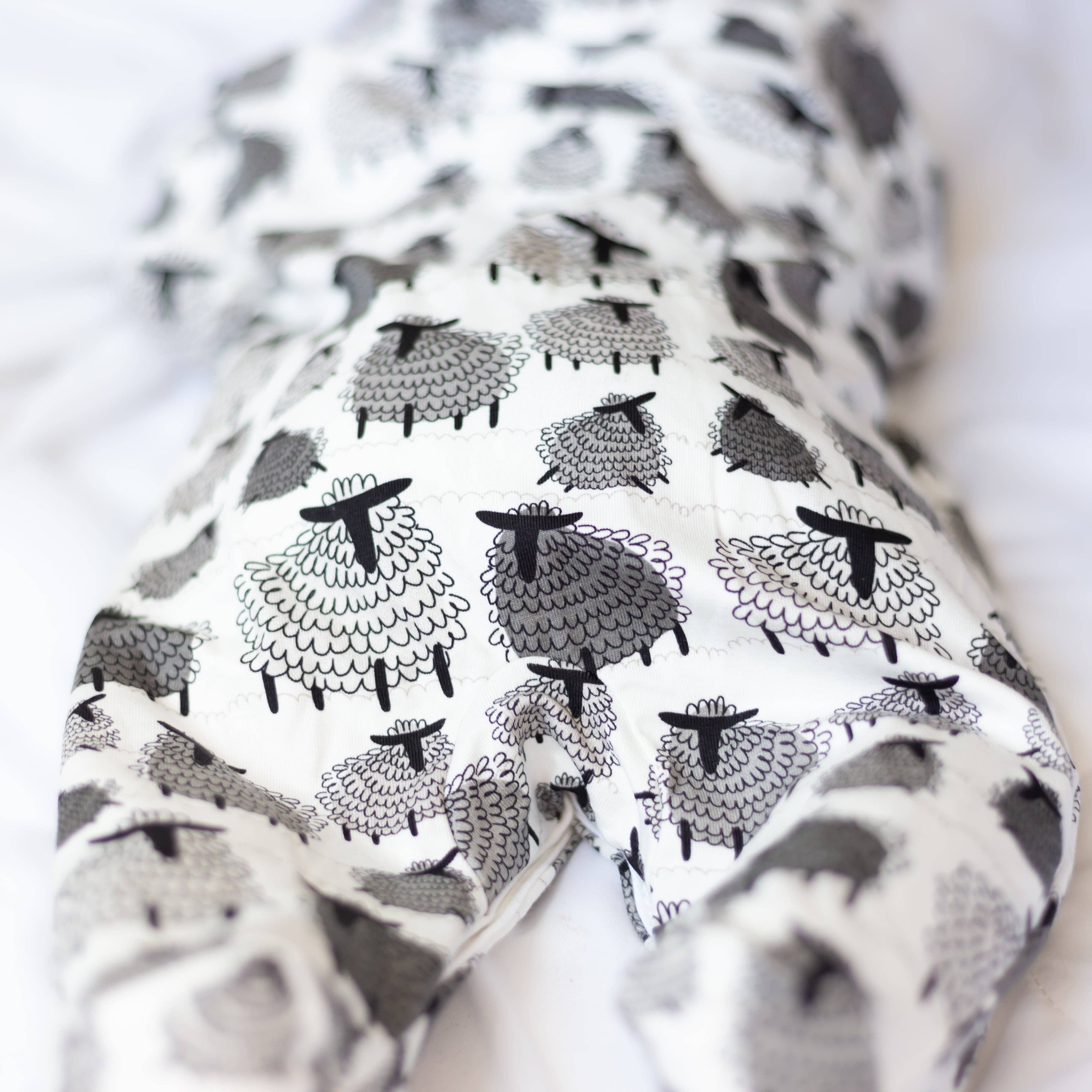 Baby's sleepsuit bottom with black and white sheep pattern on a light background