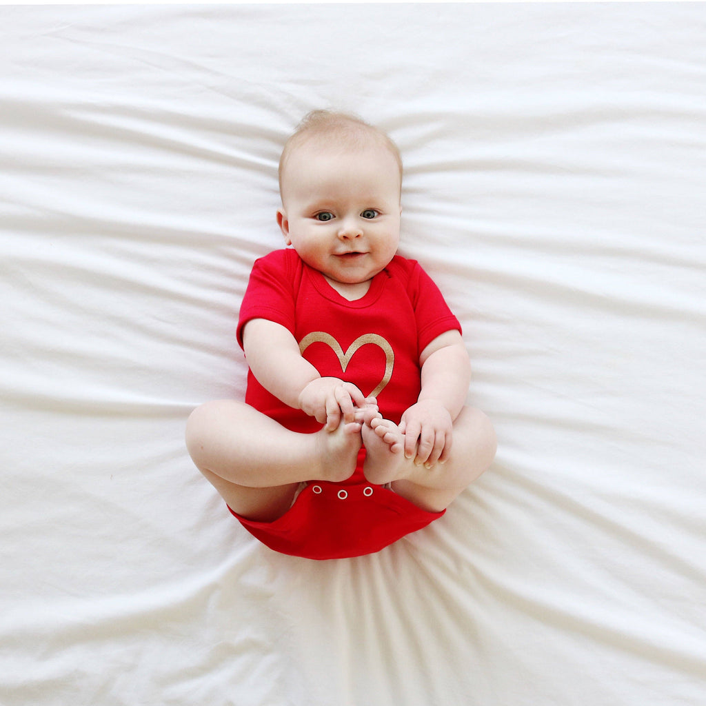 Baby wearing a red vest with a heart design on a white background