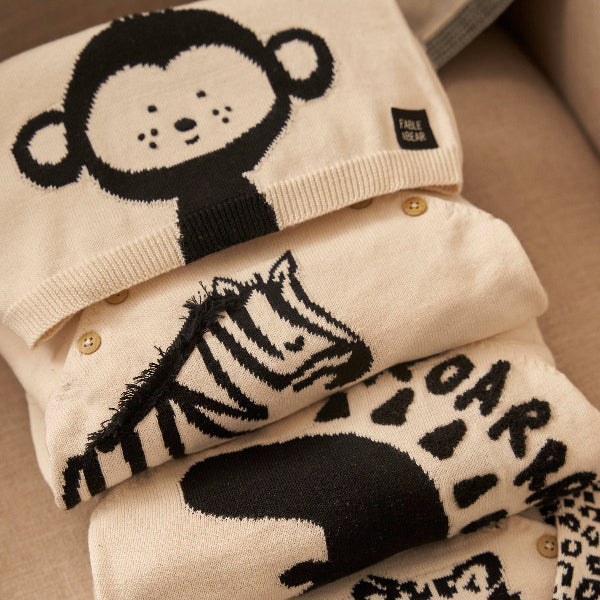 Stack of folded clothing with animal designs on a beige surface