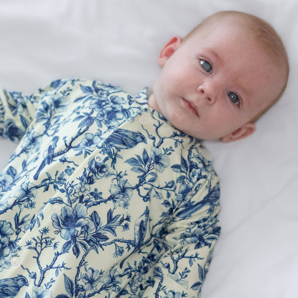 Baby wrapped in a blue floral swaddle on a white background
