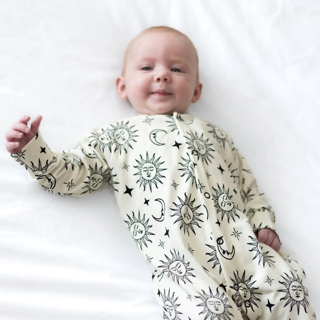 Baby wearing a sleepsuit with celestial patterns on a white background