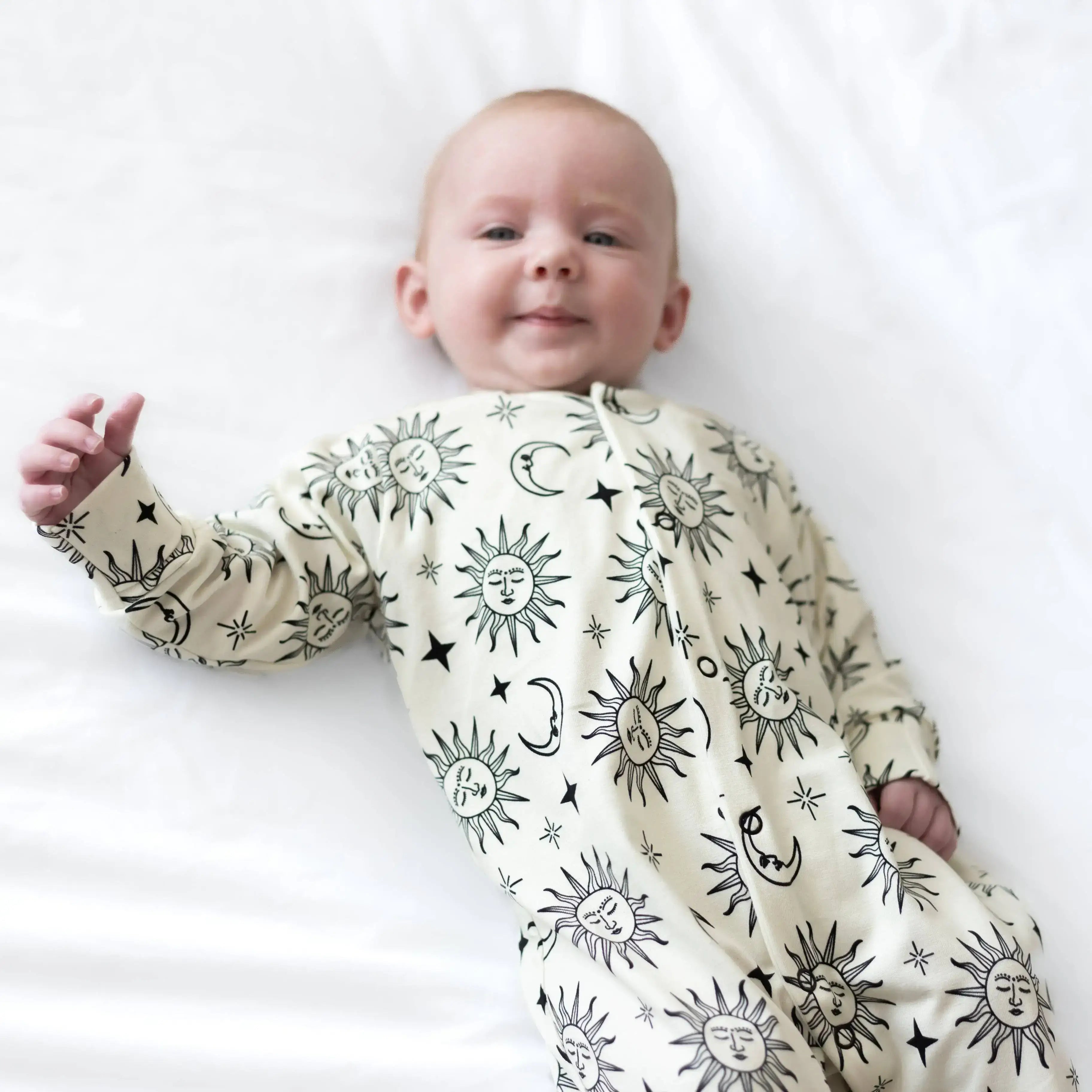 Baby wearing a sleepsuit with celestial patterns on a white background