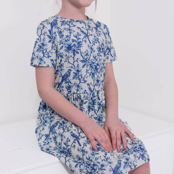 Child wearing a blue floral dress on a white background