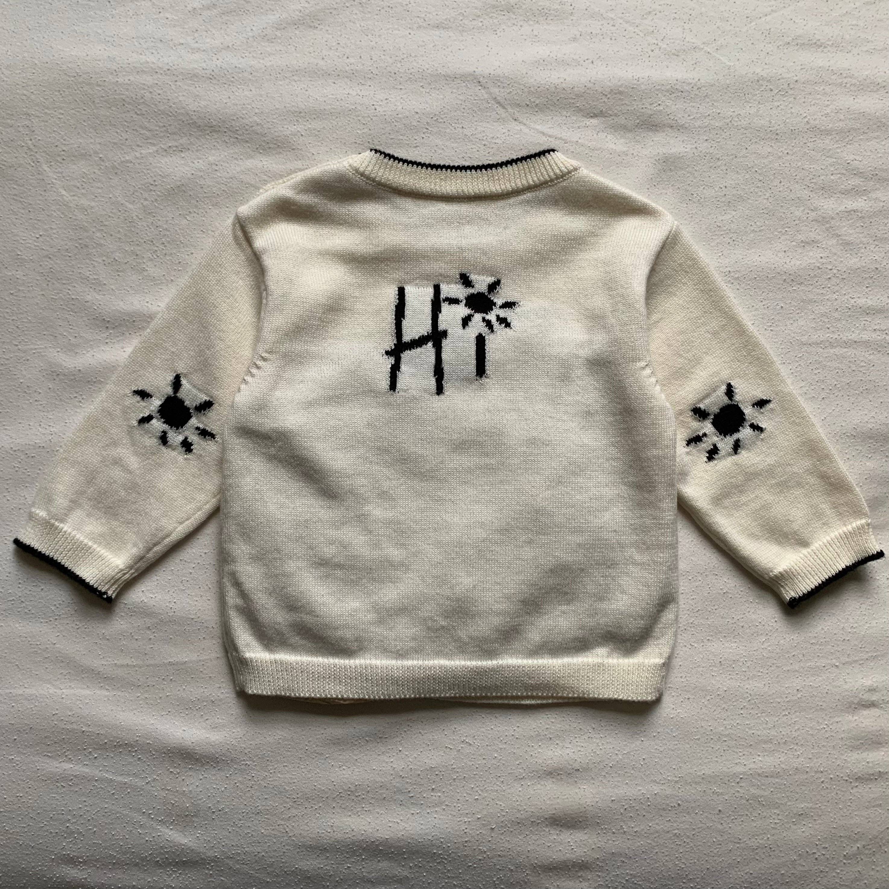 White jumper/sweater with black patterns on a gray surface