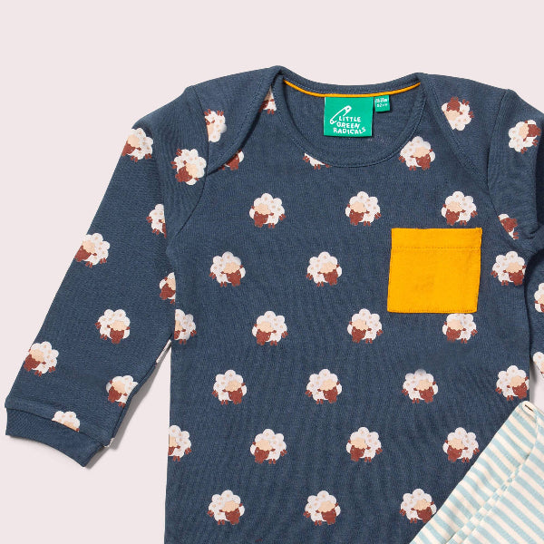 Children's navy blue long-sleeve shirt with cupcake pattern and yellow pocket on a light gray background.