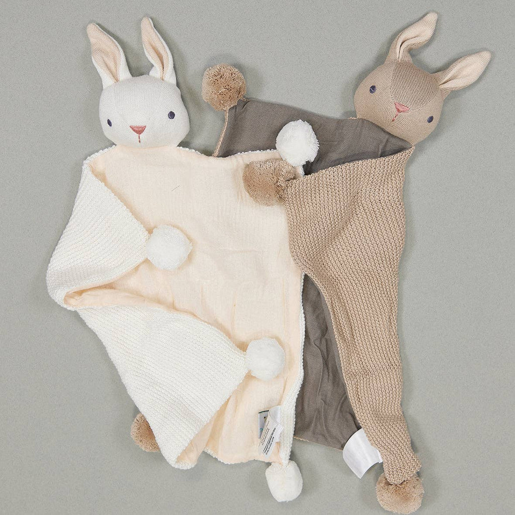 Two plush rabbit toys with a blanket on a gray background