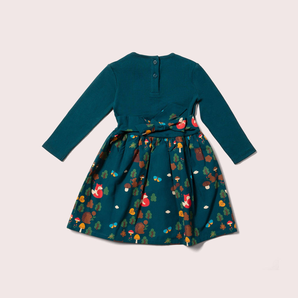 Teal dress with a colorful forest pattern on a light beige background