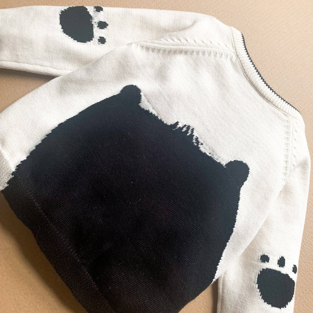 White baby jumper/sweater with black bear design on a beige background