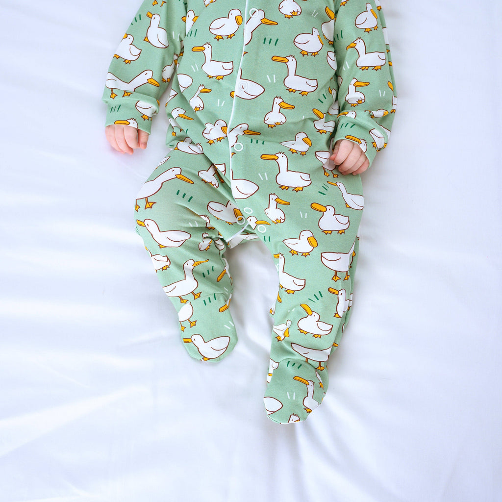 Green baby sleepsuit with duck pattern on a white background