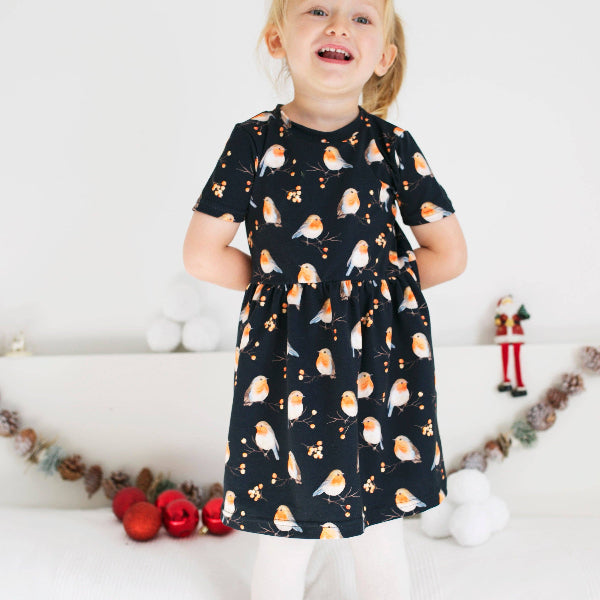 Child wearing a black dress with bird pattern in a festive setting