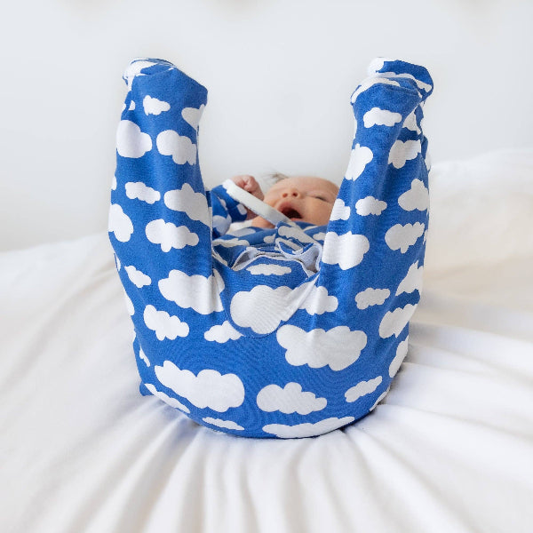 Baby in a blue and white cloud-patterned baby carrier on a white background