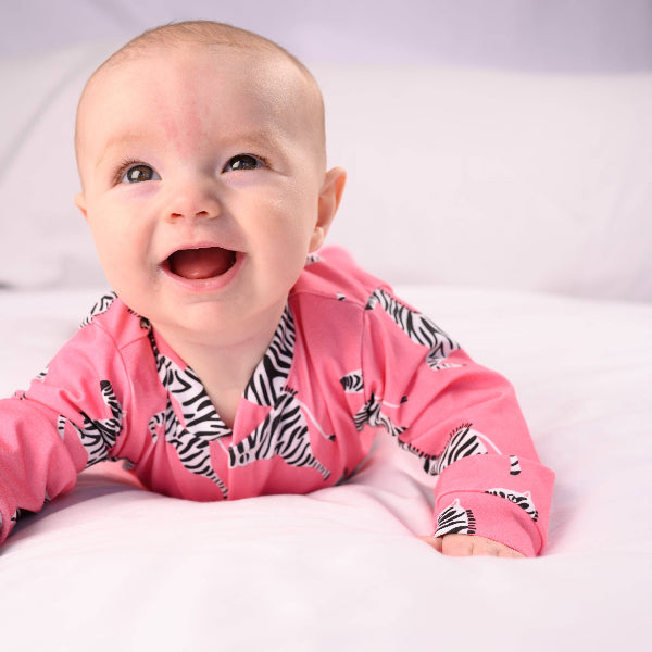 Baby wearing a pink onesie with zebra pattern on a white background