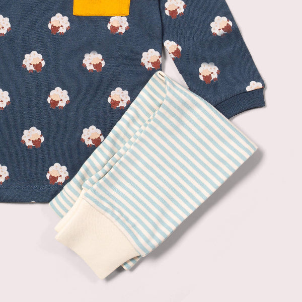 Navy sweater with cupcake pattern and folded striped fabric on a light gray background