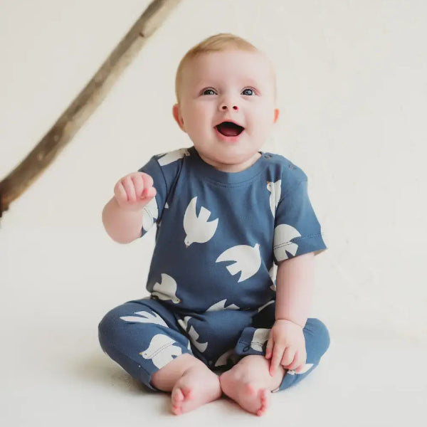 Baby wearing a 100 cotton romper with white patterns on a light background