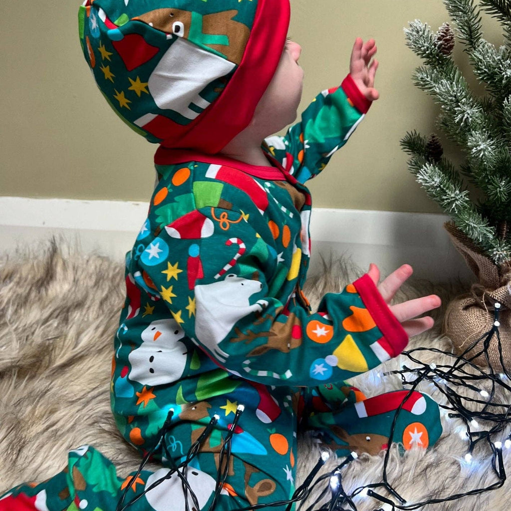 Child in festive pajamas with a Christmas tree and lights in the background