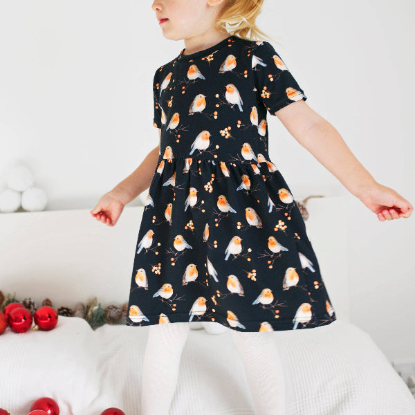 Child wearing a dress with bird pattern on a white background