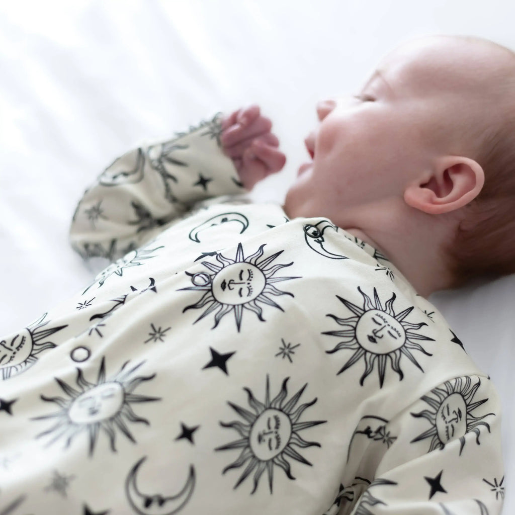 Baby wearing a sleepsuit with celestial patterns on a white background