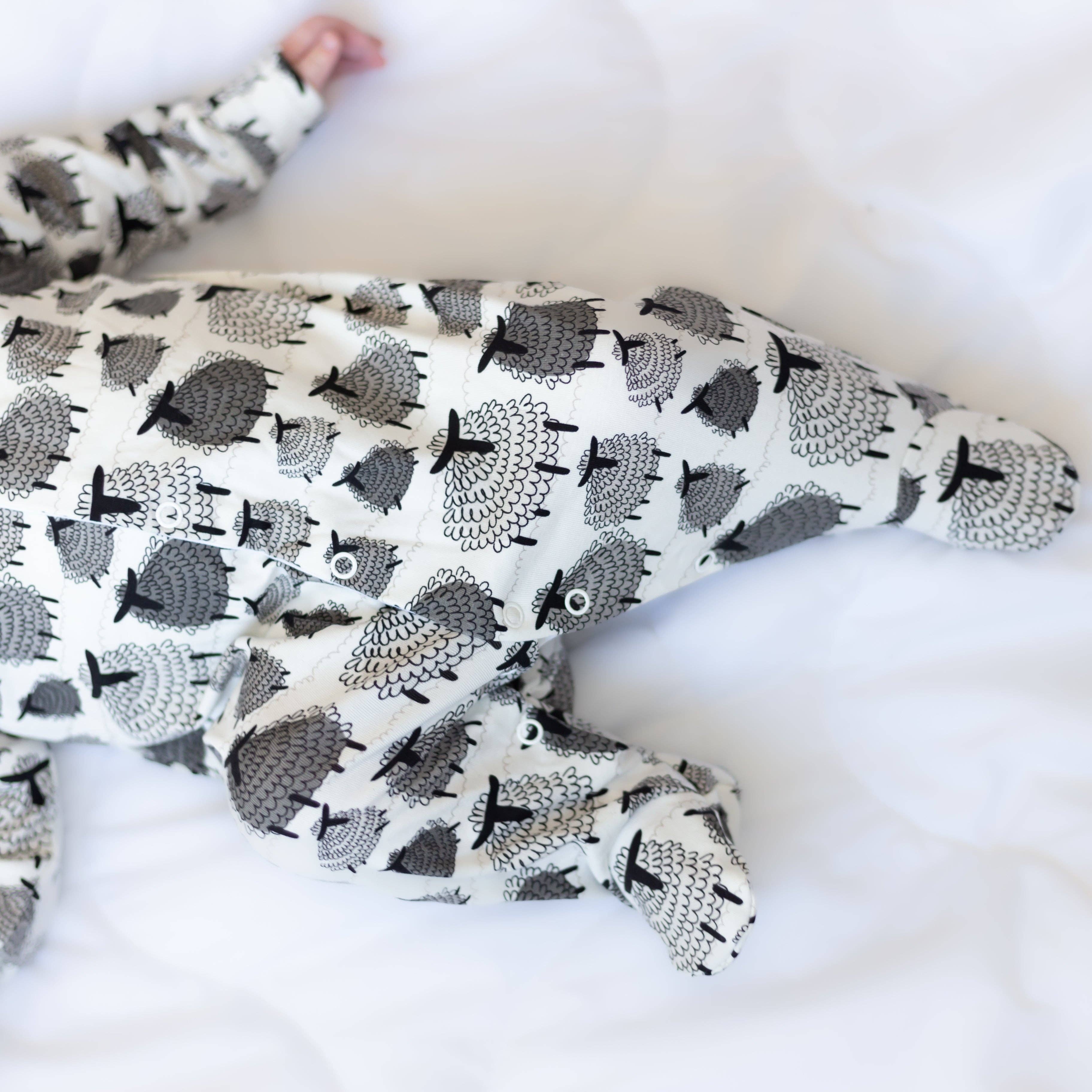 Baby sleepsuit with sheep pattern on a white blanket