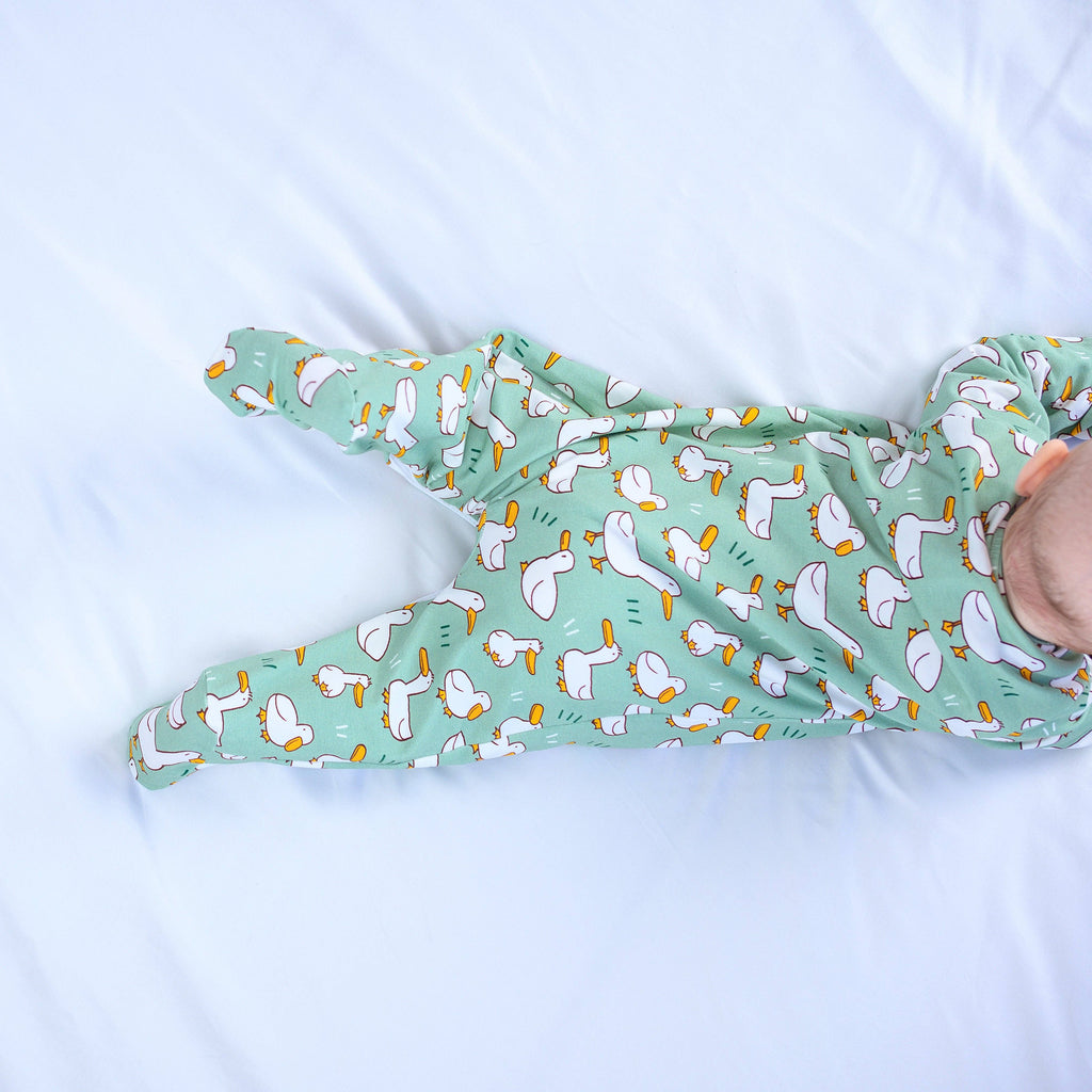 Green baby sleepsuit with cartoon pattern on a white background
