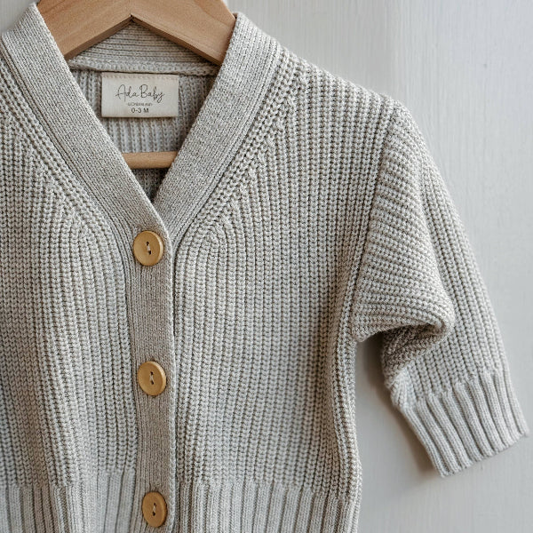 Melange knitted cardigan with wooden buttons on a hanger against a white background