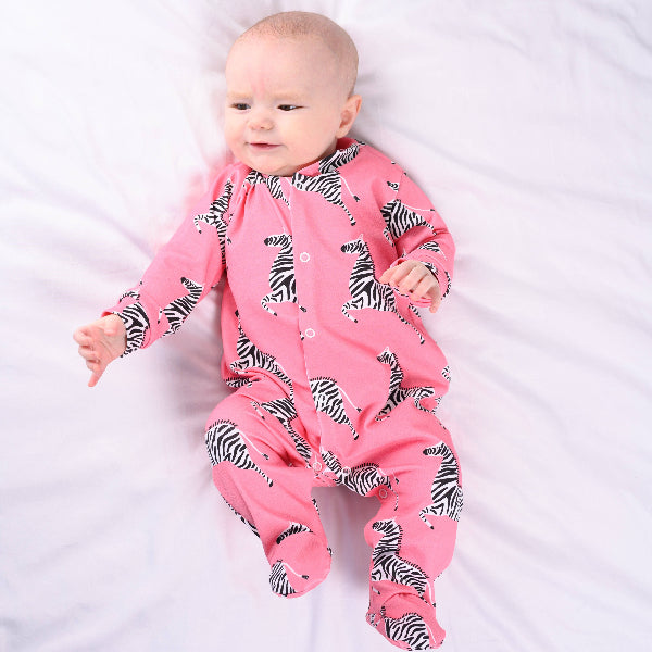 Baby wearing a pink zebra print onesie on a white background