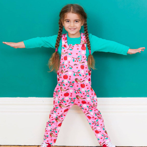 Young girl wearing a pink floral jumpsuit with a teal background