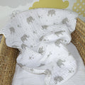 White baby blanket with gray elephant patterns draped over a wicker basket.
