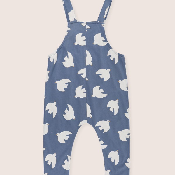 Blue dungaree back with white bird pattern on a beige background
