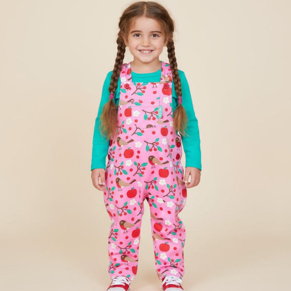 Young girl wearing a pink patterned outfit with a beige background