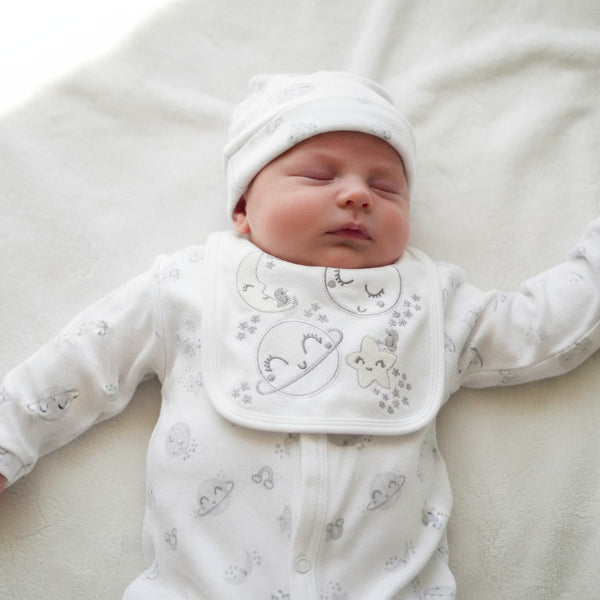 baby sleeping wearing a hat, sleepsuit, bib moon themed pattern