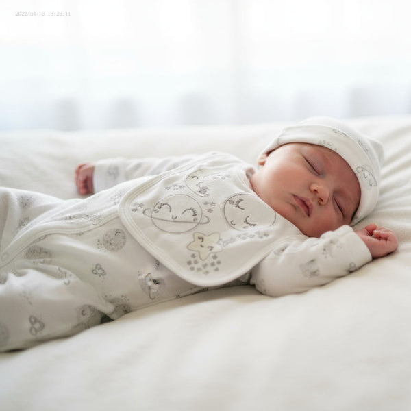 Baby sleeping wearing hat with moon, bib and sleepsuit