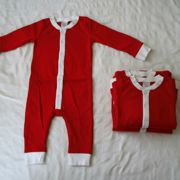 Red baby onesie with white trim on a white bedspread